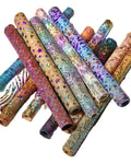 Può includere: Una collezione di rotoli di tessuto colorati, con motivi e iridescenti. Il tessuto presenta una varietà di trame, tra cui stelle, pelle di serpente e motivi geometrici.