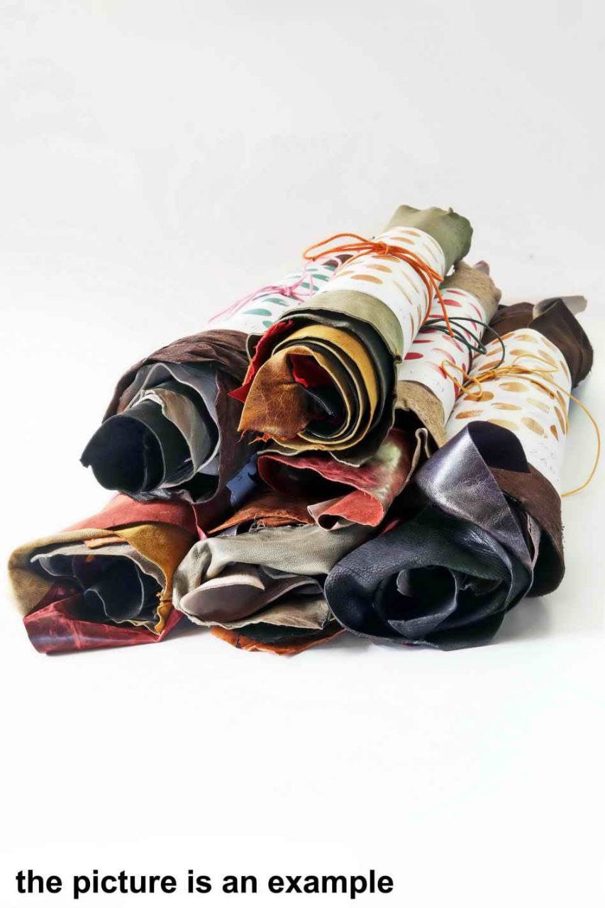 Può includere: Una collezione di pelli di cuoio arrotolate in vari colori, tra cui nero, marrone, rosso e beige. Alcuni rotoli sono legati con spago o corda. Il testo in basso recita "the picture is an example."