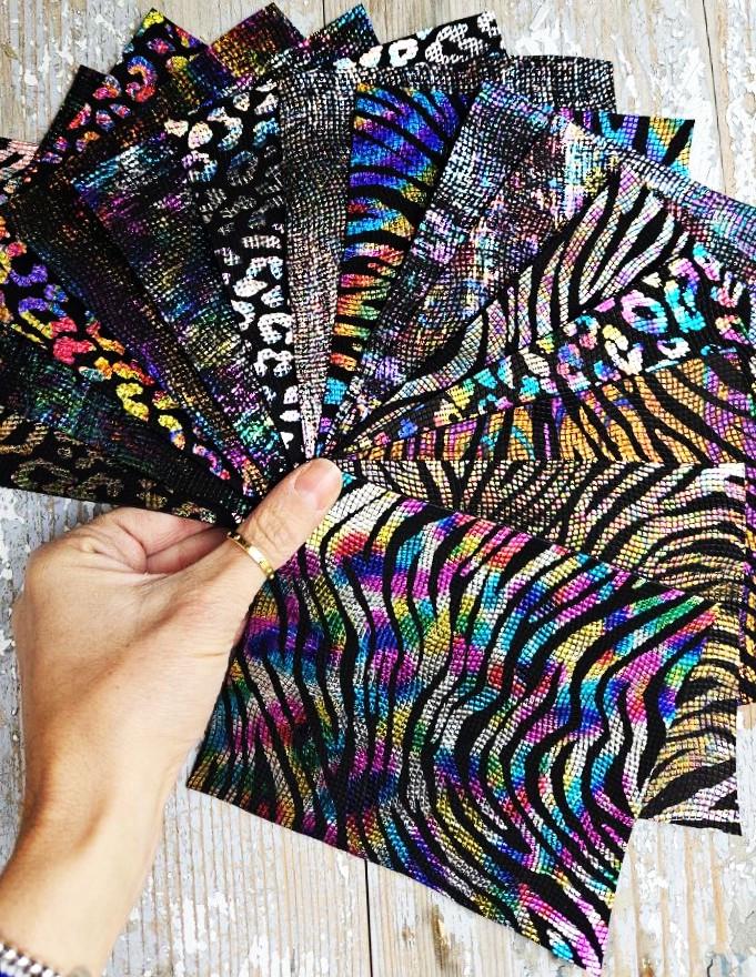 Può includere: Una collezione di campioni di tessuto iridescente con disegni di stampa animalier, tra cui motivi zebrati, leopardati e ghepardati. Il tessuto ha una finitura testurizzata e scintillante.