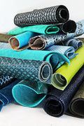 Può includere: Una collezione di pezzi di pelle arrotolati in vari colori e trame, tra cui blu, verde, nero e marrone. La pelle è disposta in una pila, con alcuni pezzi sovrapposti.