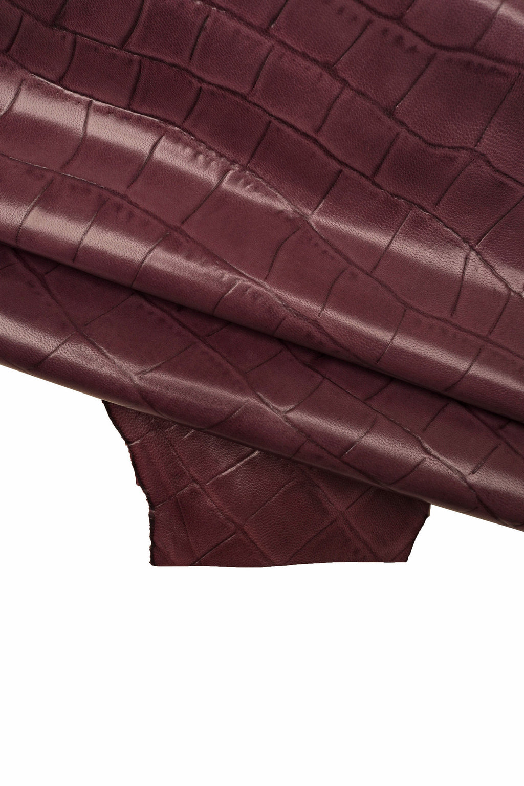 Può includere: Pelle color borgogna con un motivo goffrato a coccodrillo. La pelle è piegata a metà, mostrando la trama del materiale.