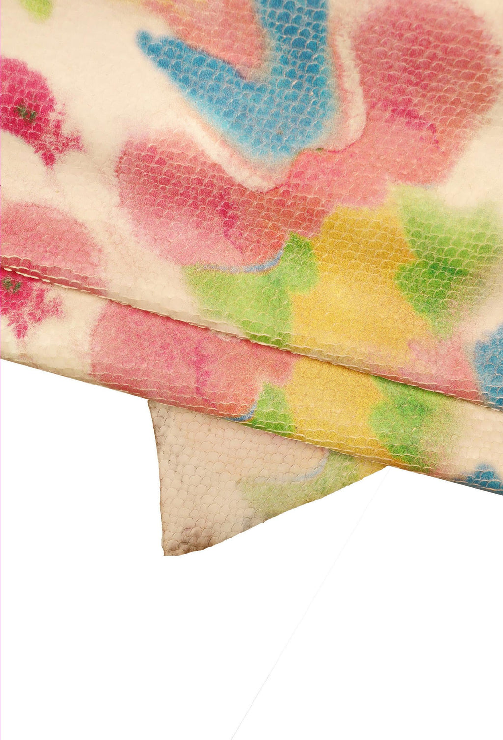 Può includere: Primo piano di un tessuto con una superficie testurizzata e un motivo floreale colorato. Il tessuto è piegato a metà, rivelando il motivo su entrambi i lati. I colori del motivo includono rosa, blu, giallo e verde.