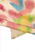 Può includere: Primo piano di un tessuto con una superficie testurizzata e un motivo floreale colorato. Il tessuto è piegato a metà, rivelando il motivo su entrambi i lati. I colori del motivo includono rosa, blu, giallo e verde.