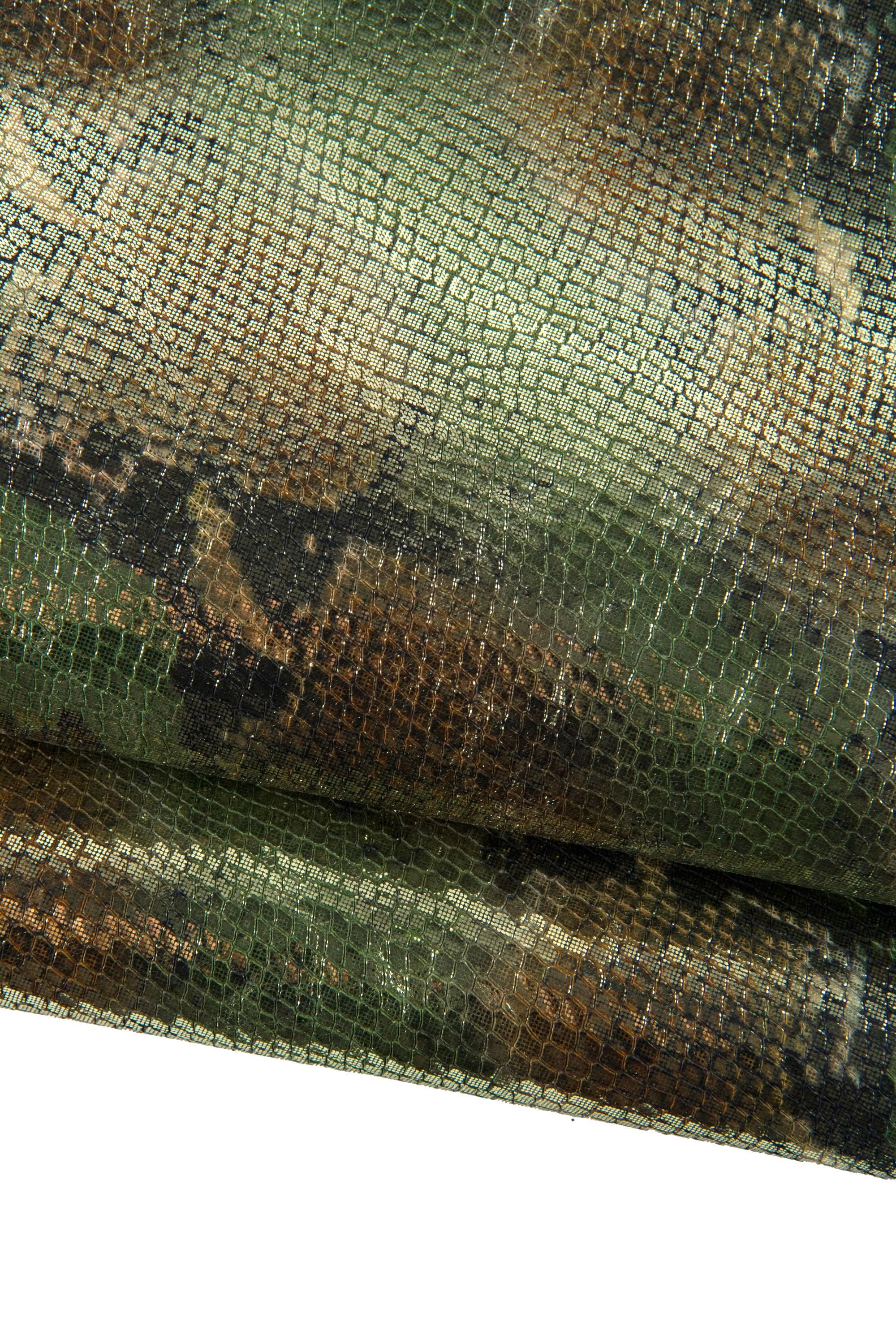 May include: Close-up of a textured fabric with a reptile-like pattern. The material features a blend of green, brown, and gold tones, creating a shimmering effect. The fabric is folded, revealing its layered texture and design.