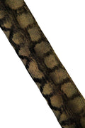 Può includere: Primo piano di una sezione di tessuto con un motivo a stampa animalier strutturato. Il design presenta una combinazione di toni neri e oro, creando un effetto scintillante. Il tessuto appare leggermente angolato su uno sfondo bianco.