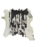 Può includere: Un tappeto in pelle di mucca con un design patchwork. Il tappeto presenta una combinazione di strisce di pelliccia bianche, nere e marroni. I bordi del tappeto sono bianchi. Il tappeto è progettato per essere posizionato sul pavimento.
