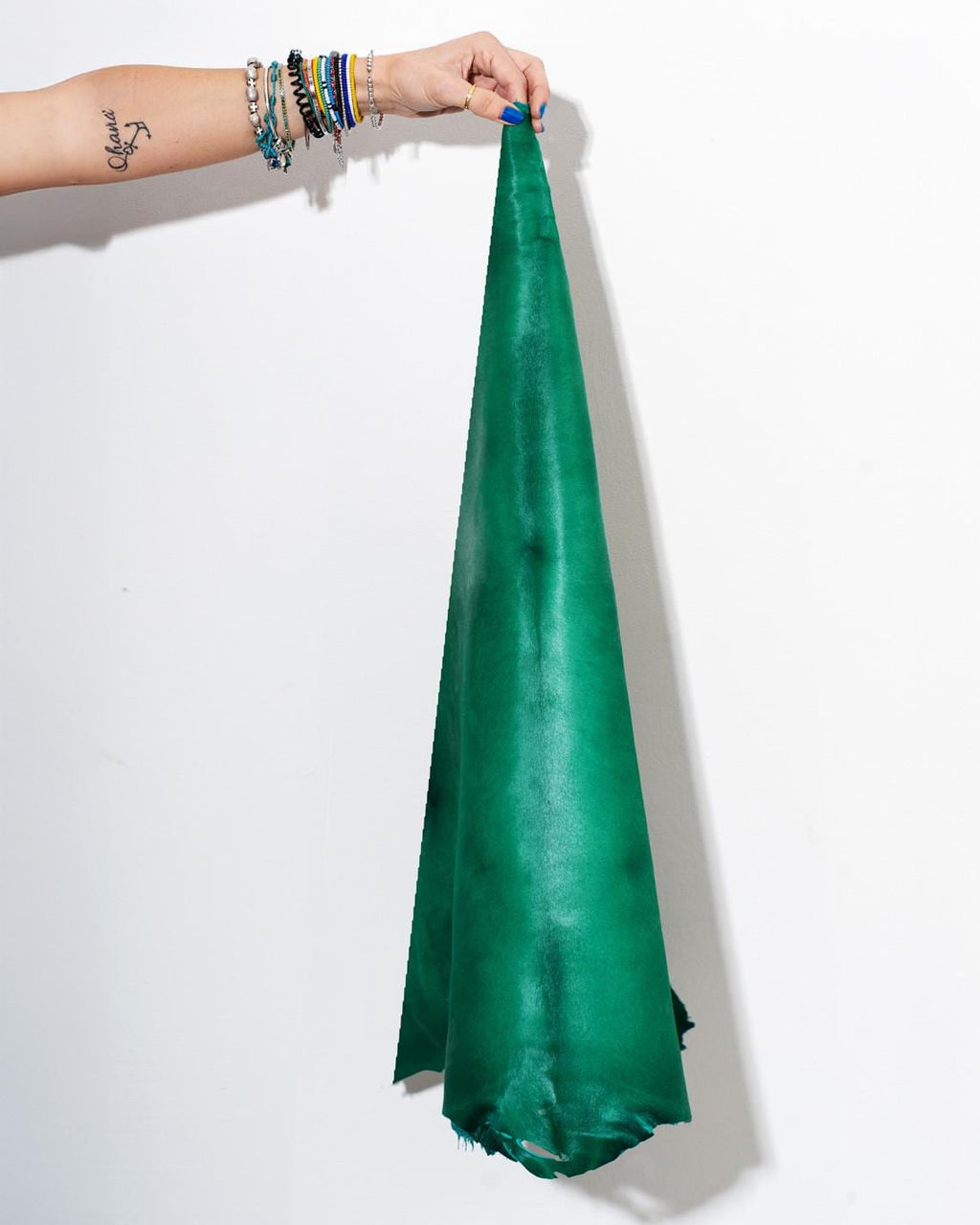 Può includere: Un singolo pezzo di pelle liscia e vibrante color verde smeraldo, tenuto in verticale. Il materiale presenta una tonalità verde satura e coerente con sottili variazioni di tono sulla superficie, mostrando una finitura opaca naturale.