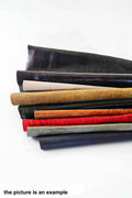 Può includere: Una pila di pelli di cuoio di vari colori, tra cui nero, crema, beige, arancione, rosso, grigio e blu navy. La pelle è arrotolata e impilata, mostrando le diverse trame e i colori disponibili. Il testo in basso dice "the picture is an example."