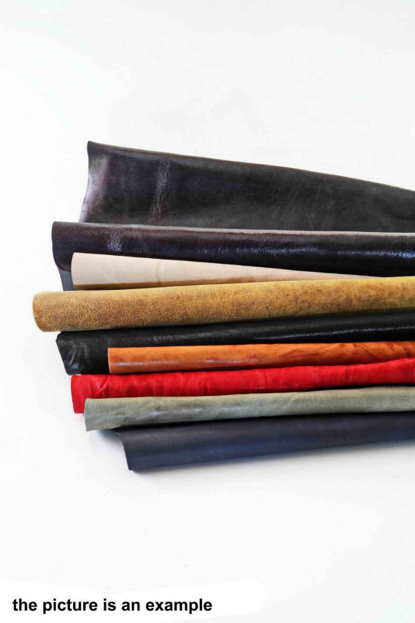 Può includere: Una pila di pelli di cuoio di vari colori, tra cui nero, crema, beige, arancione, rosso, grigio e blu navy. La pelle è arrotolata e impilata, mostrando le diverse trame e i colori disponibili. Il testo in basso dice "the picture is an example."