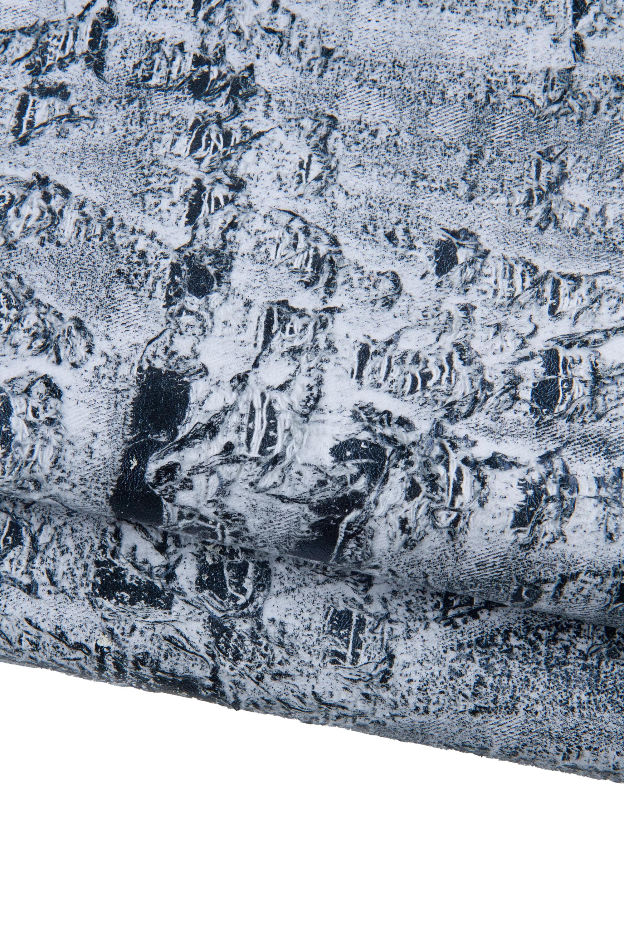 Può includere: Primo piano di materiale strutturato con un aspetto invecchiato e screziato. La superficie è prevalentemente bianca con accenti grigio scuro e neri, creando una texture ruvida, quasi simile alla pietra. Il materiale sembra essere piegato o stratificato.