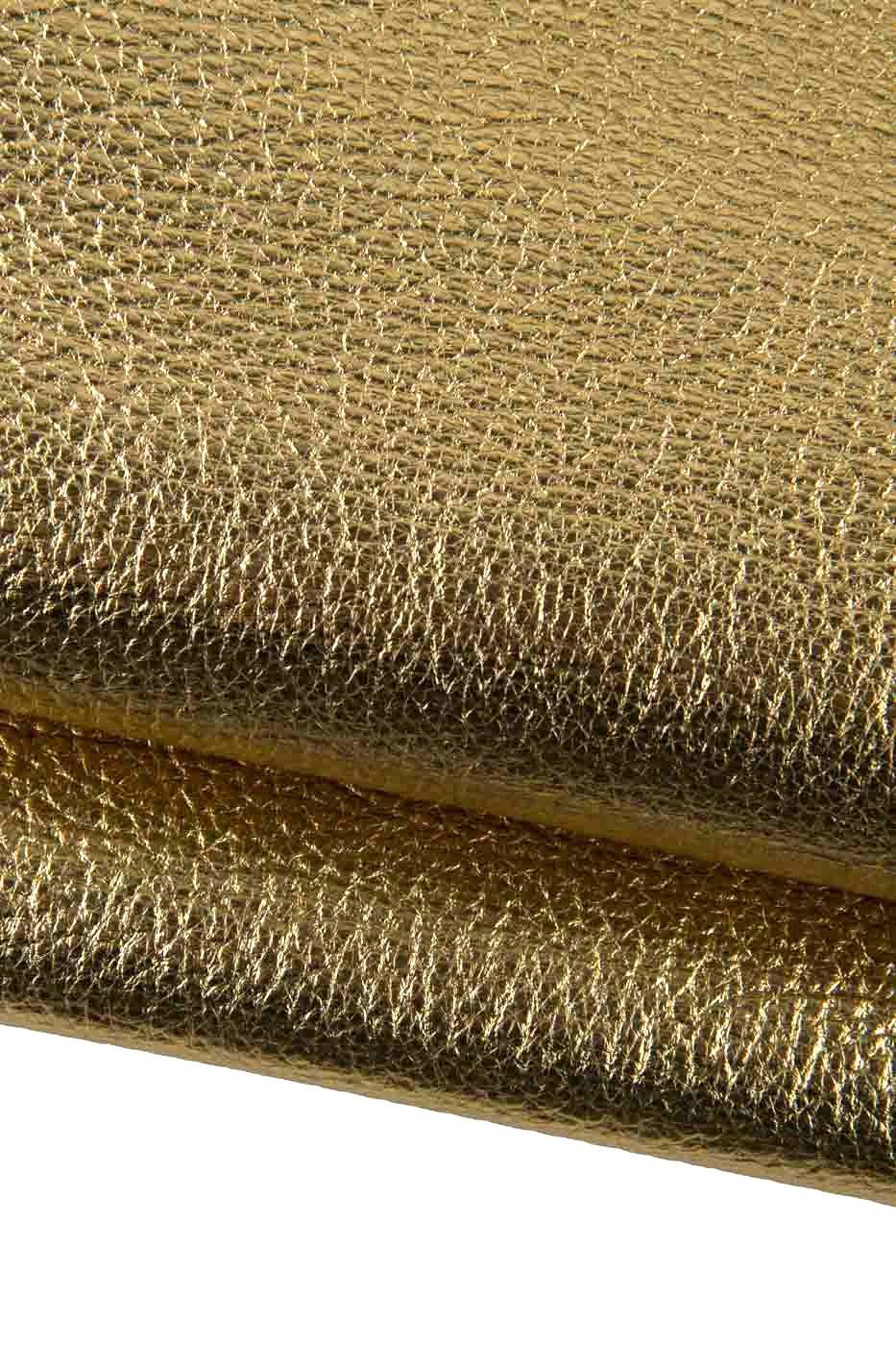 Può includere: Primo piano di un materiale dorato e strutturato. La superficie presenta un motivo sottile e irregolare, con una leggera lucentezza. Il materiale sembra essere ripiegato su se stesso, creando un effetto a strati. L'impressione generale è di lusso e ricchezza.