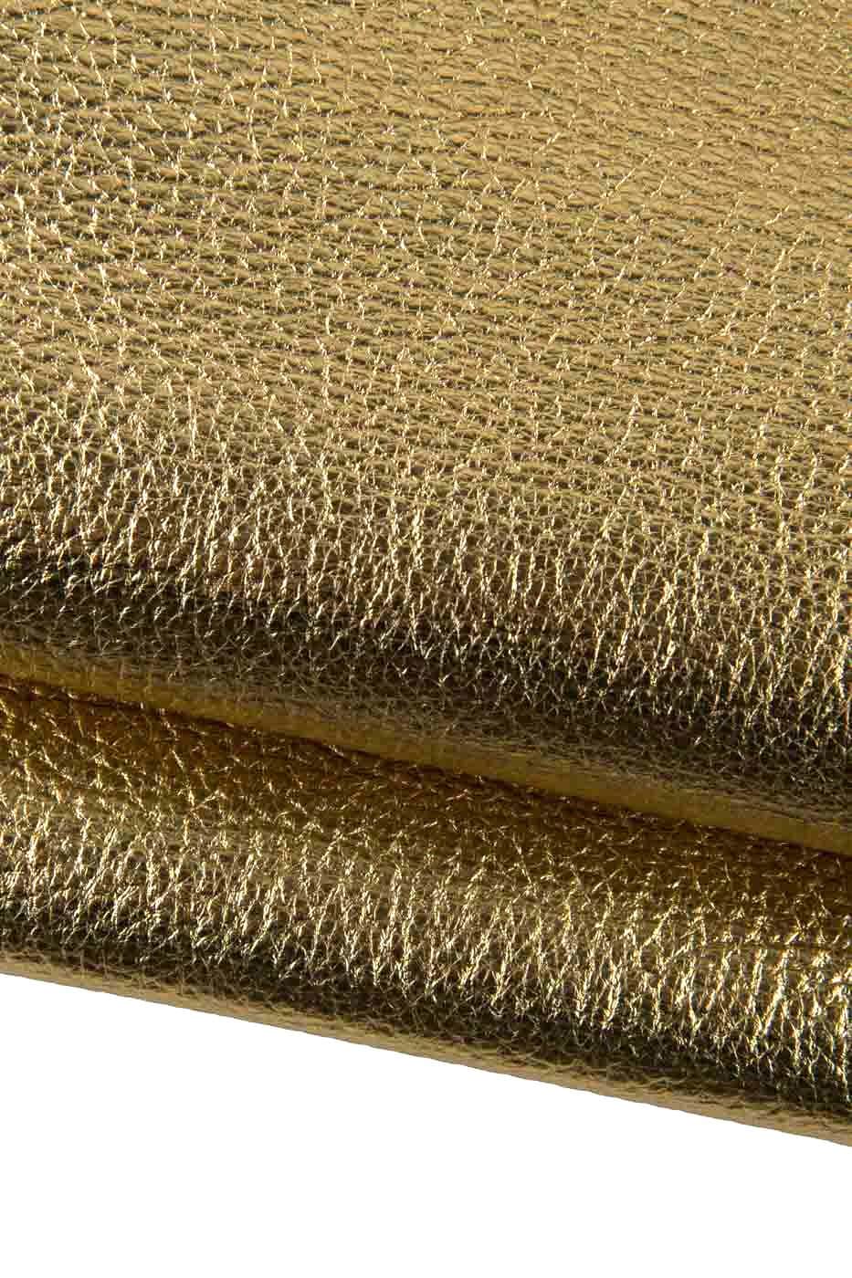 Può includere: Primo piano di un materiale dorato e strutturato. La superficie presenta un motivo sottile e irregolare, con una leggera lucentezza. Il materiale sembra essere ripiegato su se stesso, creando un effetto a strati. L'impressione generale è di lusso e ricchezza.