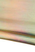 Può includere: Primo piano di tessuto iridescente con superficie strutturata. Il materiale mostra una gamma di colori, tra cui oro, rosa e verde, creando un effetto scintillante. Il tessuto è piegato, rivelando la sua struttura a strati.