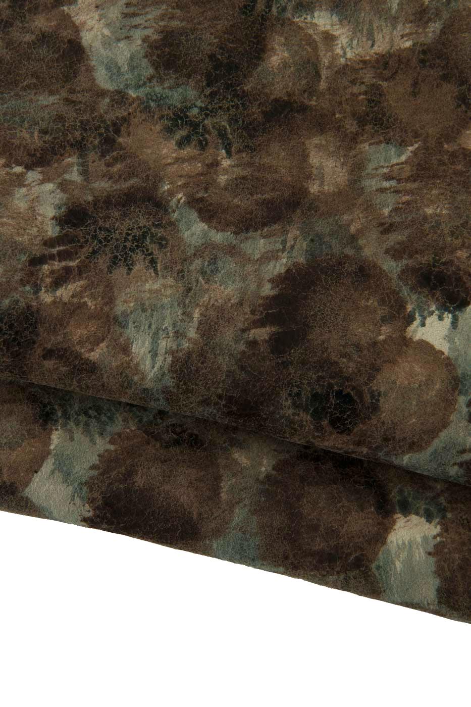 Può includere: Primo piano di un tessuto strutturato con un motivo screziato nei toni del marrone, verde e blu. Il tessuto sembra avere un aspetto invecchiato, con variazioni di colore e consistenza. Il materiale è piegato, rivelando il suo spessore e la sua flessibilità.