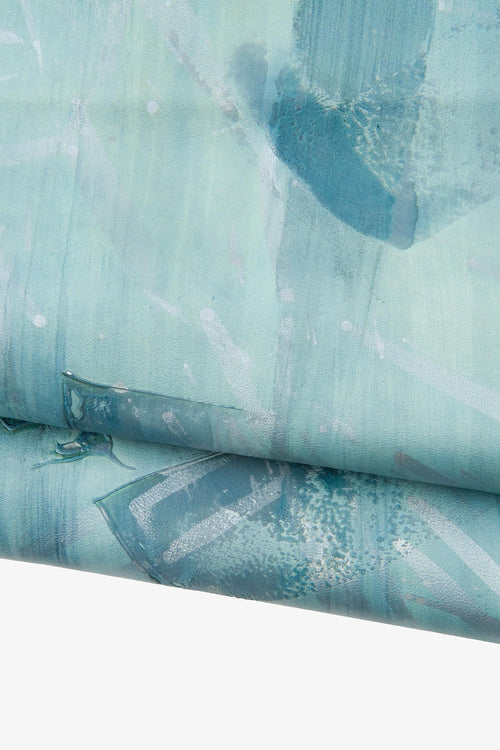 Può includere: Stampa artistica astratta con sfumature di verde acqua e blu con pennellate bianche. L'opera d'arte ha un aspetto strutturato, con un bordo arrotolato che rivela il retro della tela. Il tema generale è un design moderno e artistico.