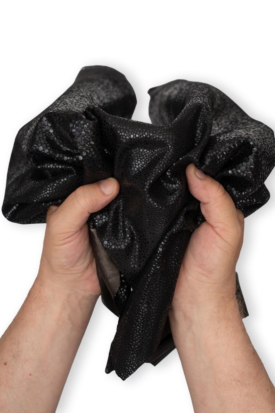 Può includere: Un pezzo di pelle nera caratterizzato da una distinta texture granulosa e in rilievo su tutta la superficie. Il materiale è flessibile e pieghevole, con una finitura opaca e sottili riflessi di luce sui piccoli rilievi arrotondati del tessuto.