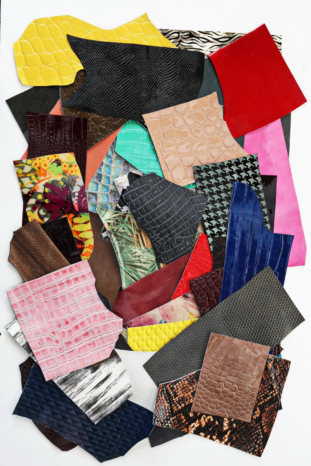 Può includere: Assortimento di ritagli di pelle colorati in varie trame e motivi, tra cui coccodrillo, serpente e pied de poule. I ritagli sono disposti in un mucchio casuale su uno sfondo bianco.